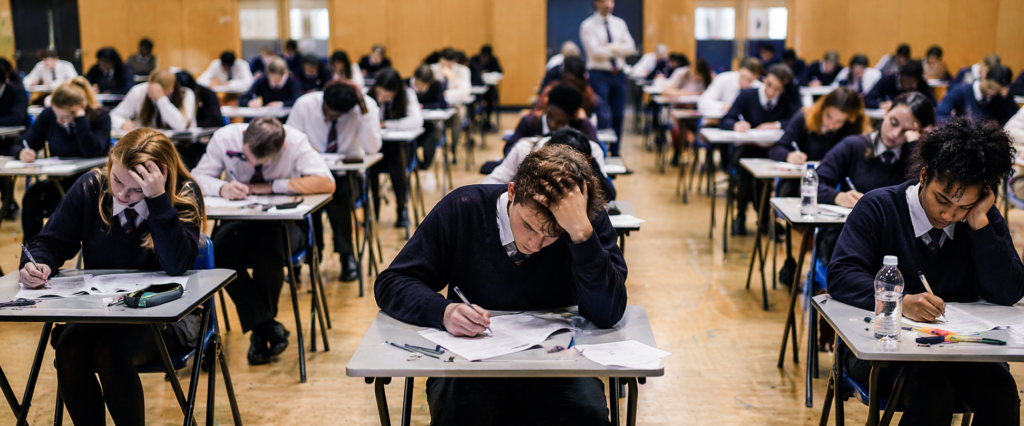 Students sitting exams in a hall feeling stressed and under pressure during GCSE and A Level exam season