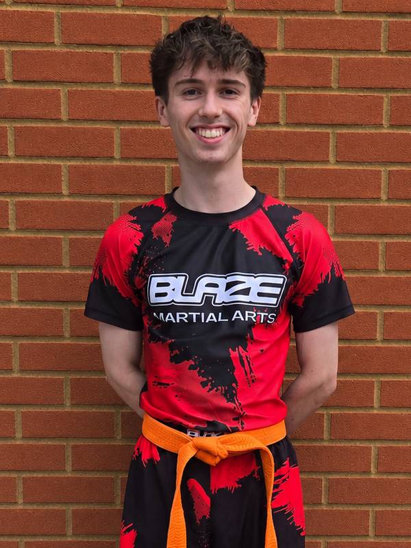 Dylan Stephen from Blaze Martial Arts wearing a kickboxing uniform and orange belt, promoting martial arts classes for children, teens and adults in Windsor, Ascot, Bracknell and Wokingham.