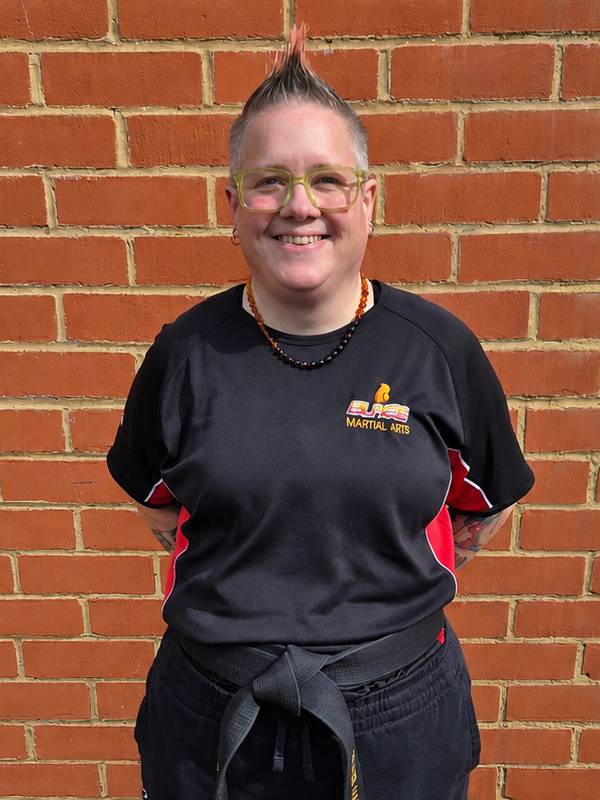 Sue Woodley from Blaze Martial Arts wearing a kickboxing uniform and black belt, promoting martial arts classes for children, teens and adults in Windsor, Ascot, Bracknell and Wokingham.